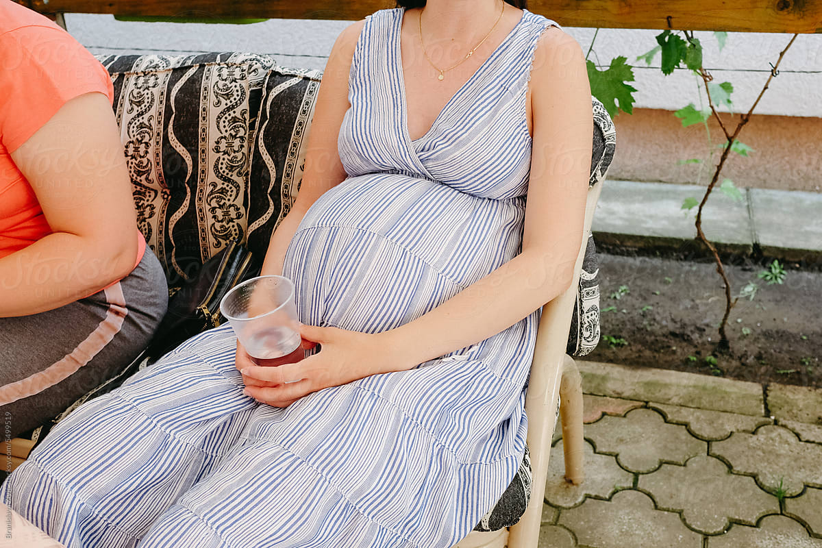 Anonymous pregnant woman sitting and drinking beer