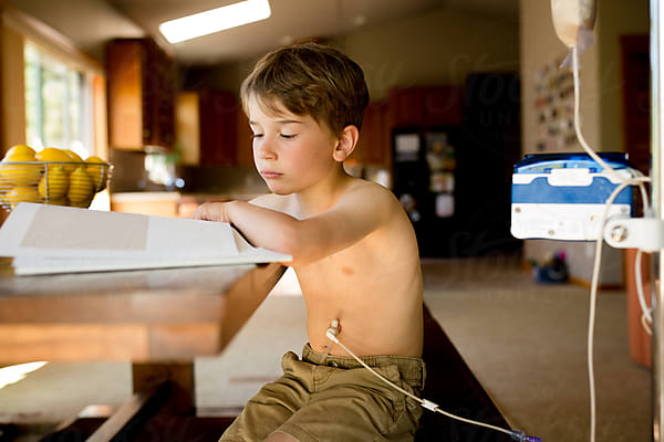 Boy Reads On Couch In Front Of Rainbow Streamers by Stocksy Contributor  Jennifer Bogle - Stocksy