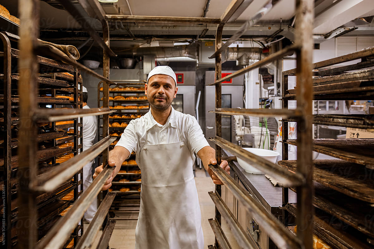Portrait of a pastry chef in white uniform resting in the pastry shop