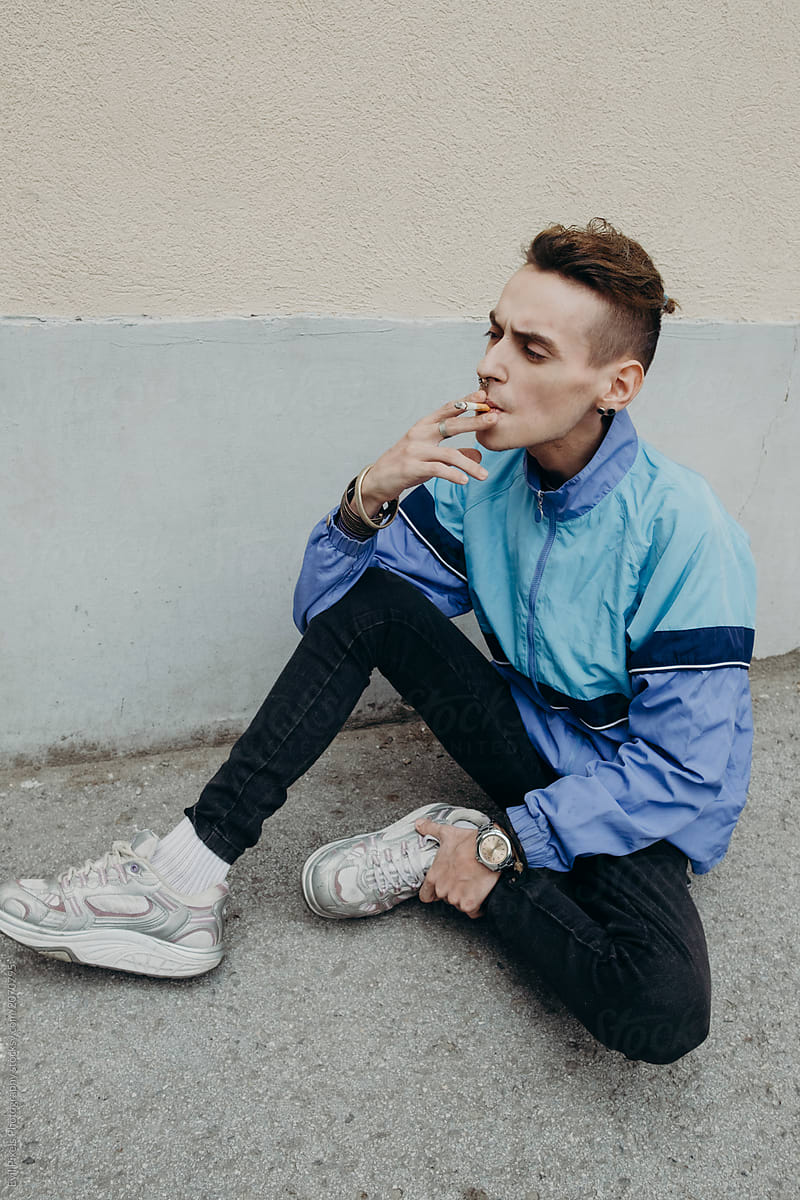 Portrait of a skinny young male model with autentic style smoking cigarette