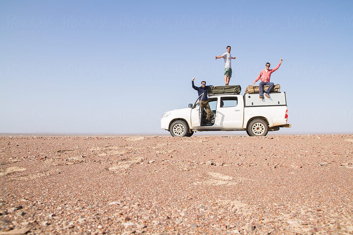 Group of happy friends on top of an off-road vehicle in the middle of the desert - Adventure travel