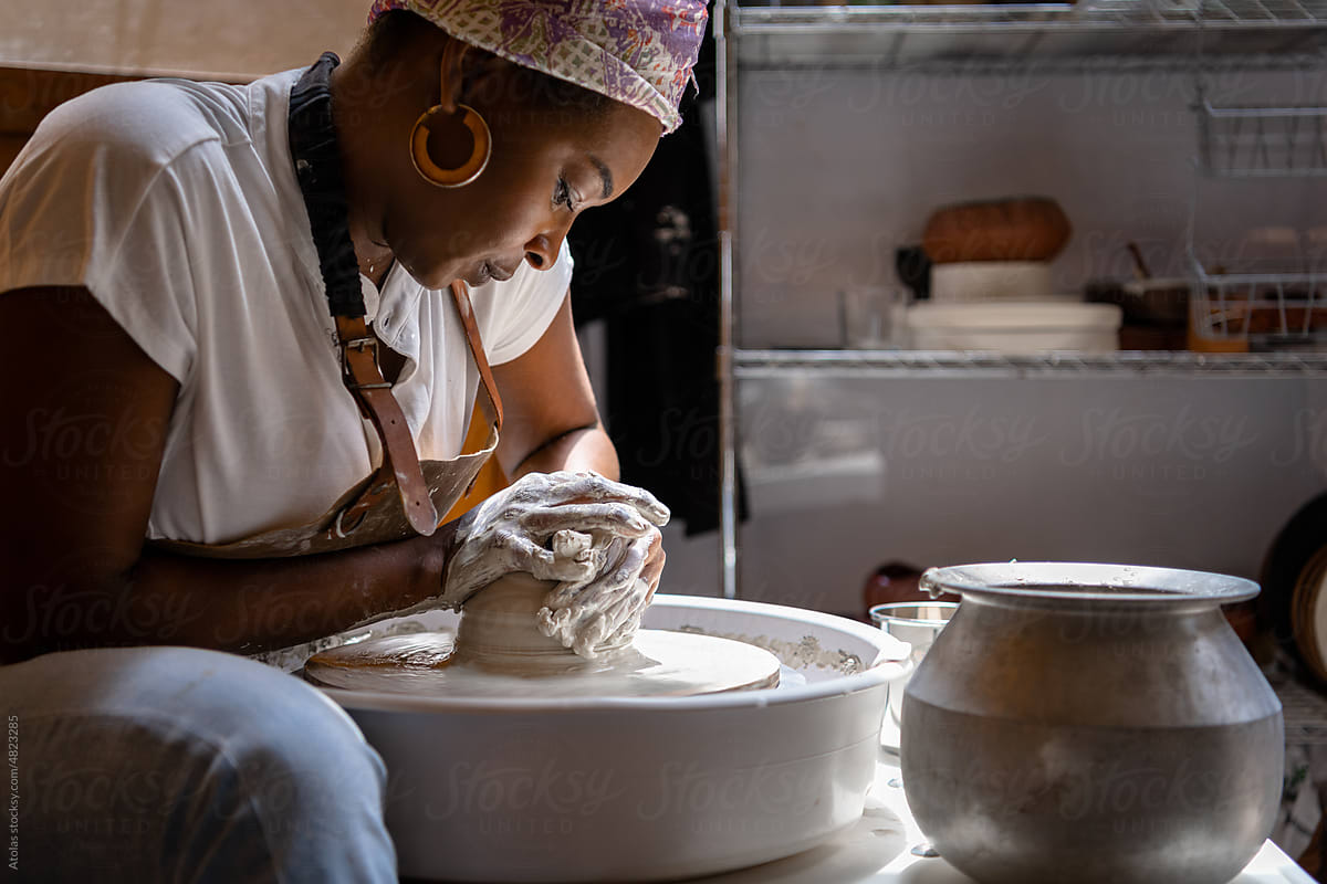 Woman working with clay on the pottery wheel