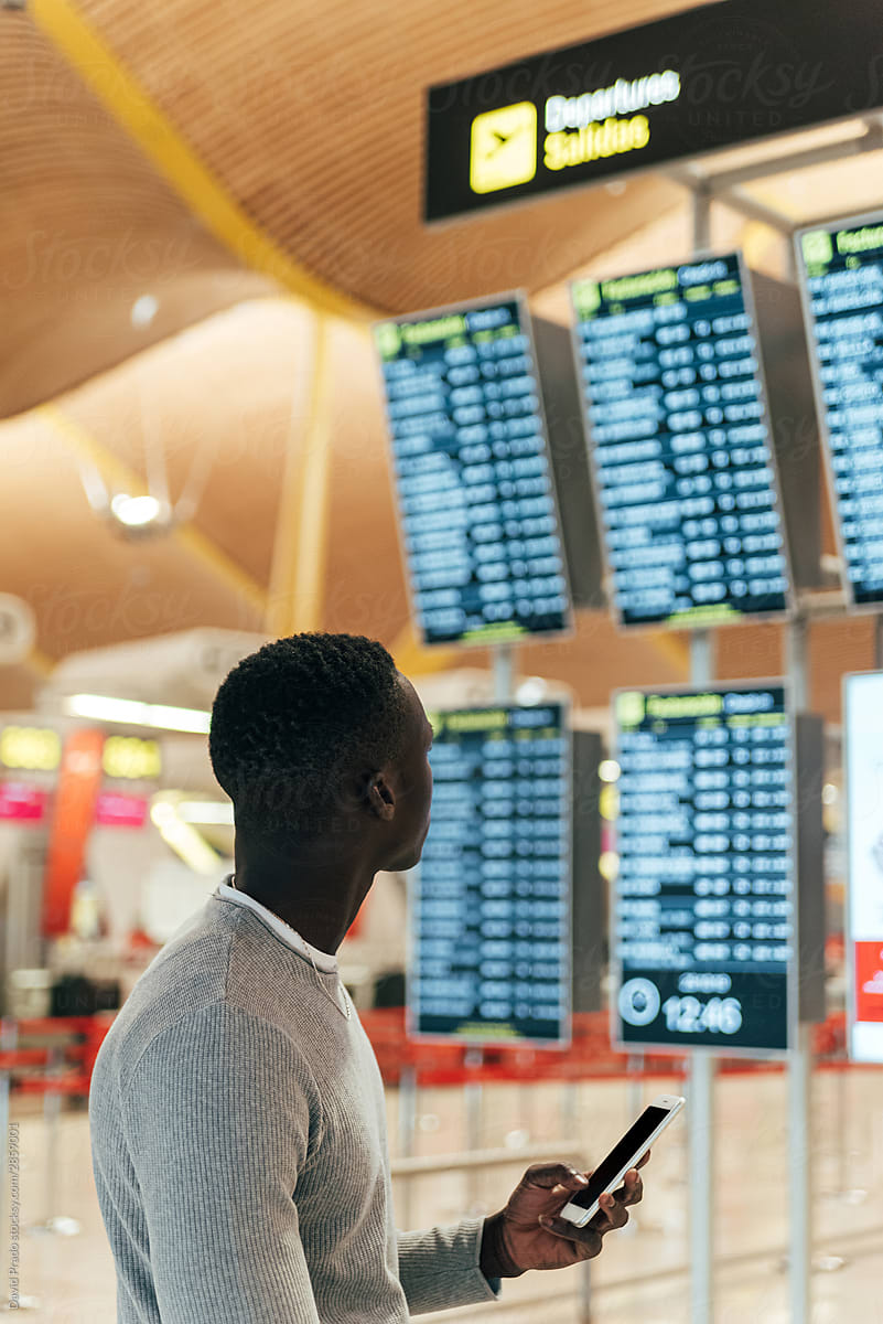 black man looking at the timetable information panel in the airp