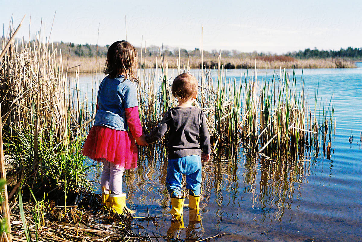 Brother and Sister Wearing Rubber Boots Play Outside Together