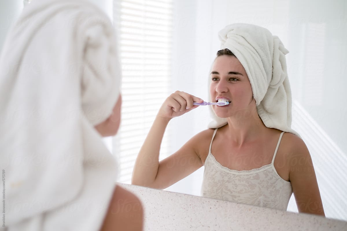 Woman Looking Herself In The Mirror And Brushing Her Teeth