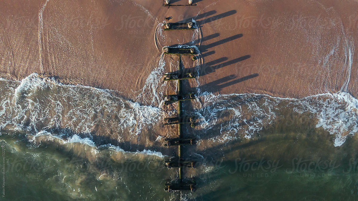 drone photo of the ocean wave rushing old pier poles