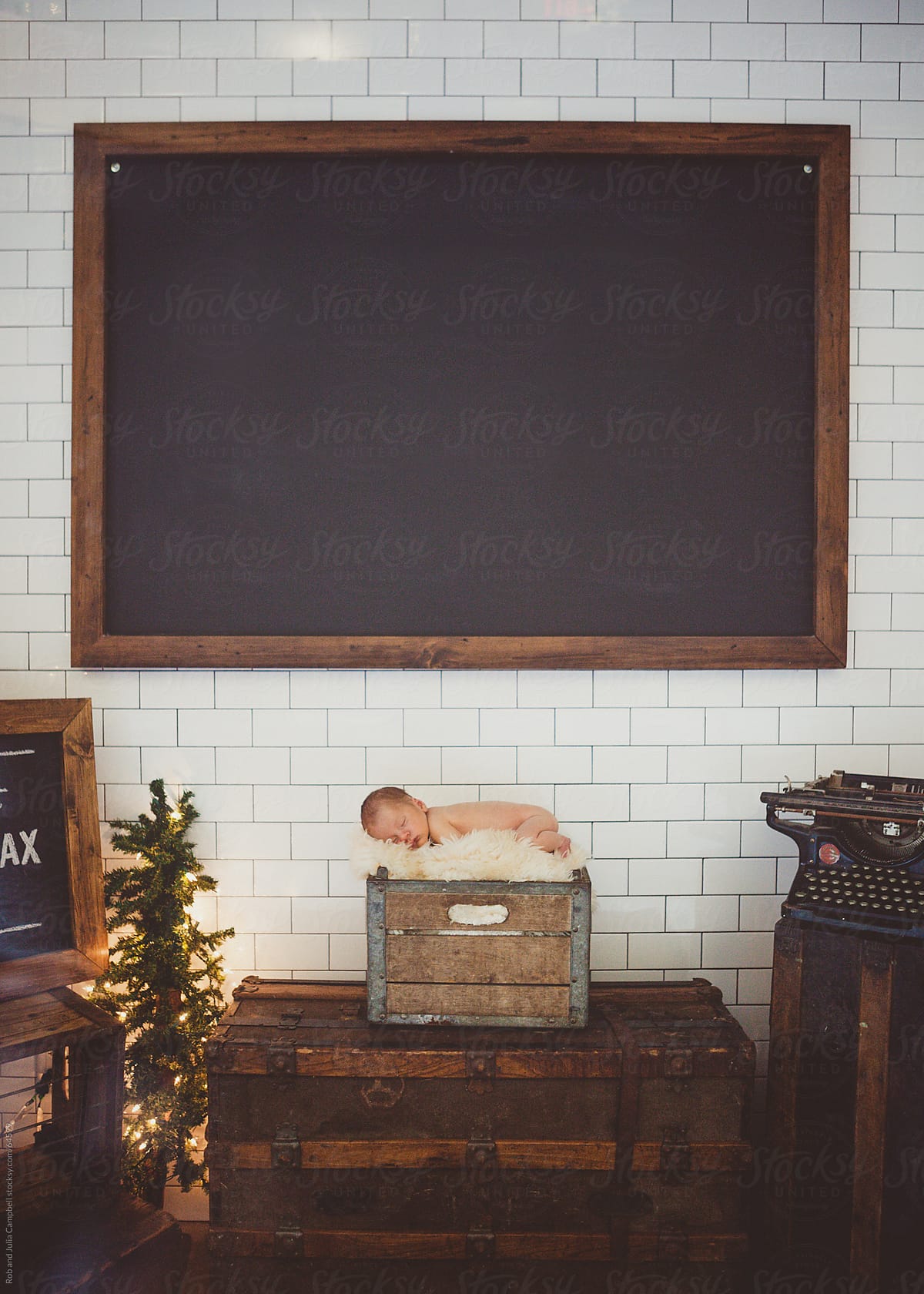Newborn baby sleeping peacefully with black chalkboard behind