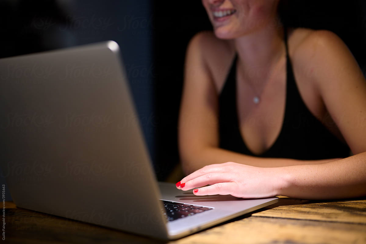 Woman with red nails using laptop.