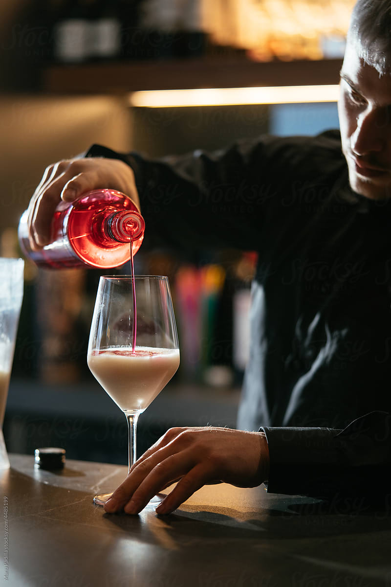 Bartender pouring alcohol into glass with cream liqueur