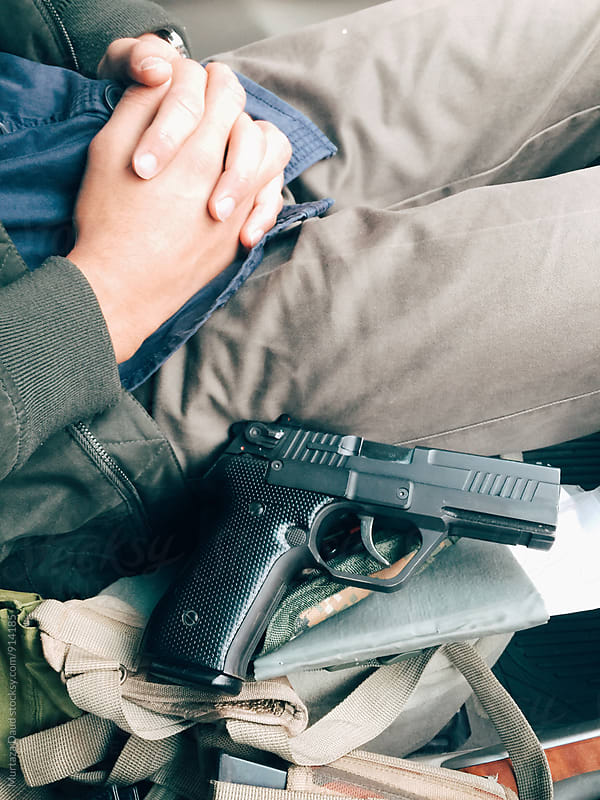 A person sitting with a handgun by his side