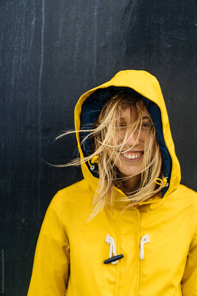 Cheerful woman in raincoat on windy day