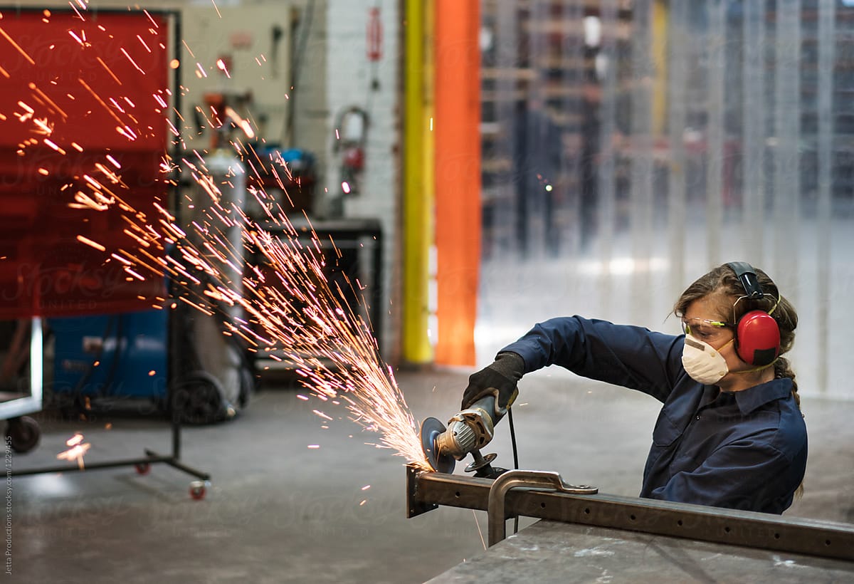 Female factory worker creates a spray of sparks