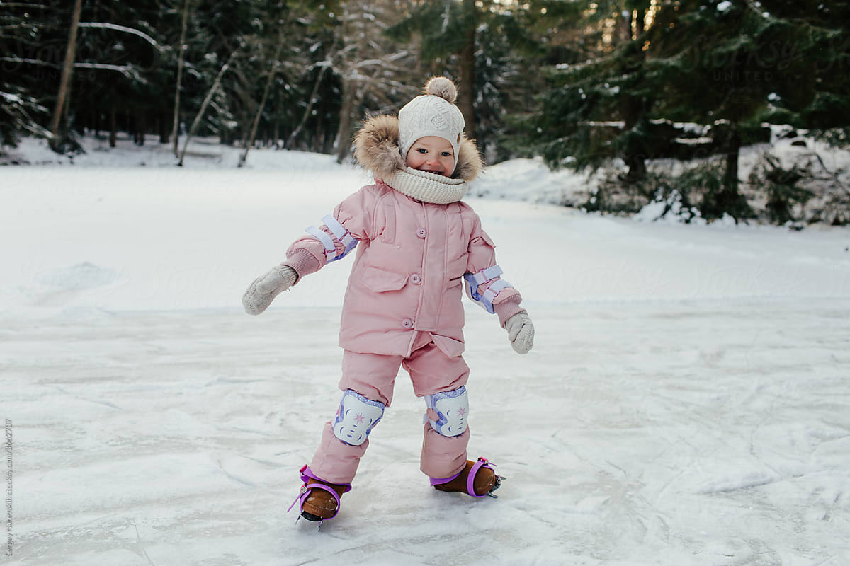 Happy little child skating on ice in forest