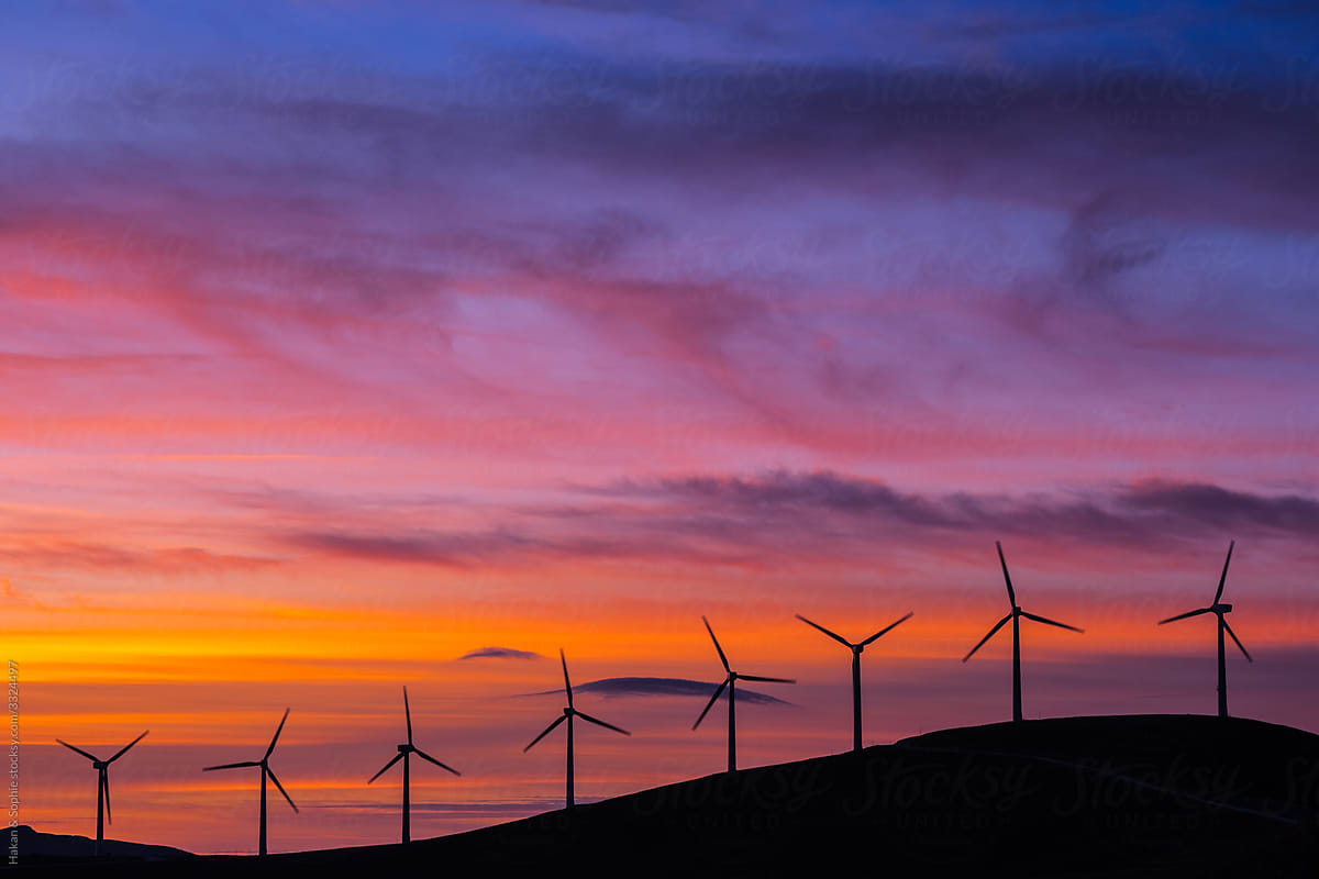 wind turbines in purple and orange setting sun