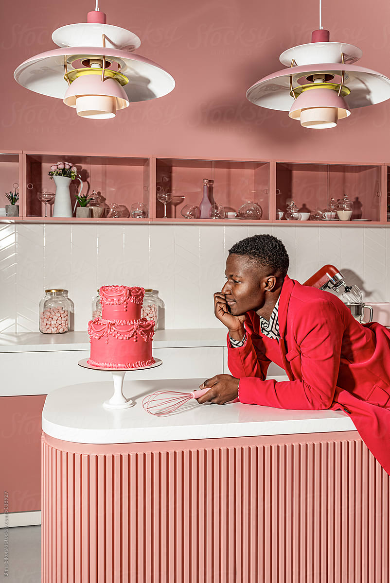 A fashionable guy in the kitchen admires a cooked cake