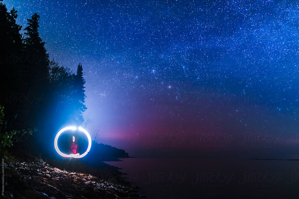 Man Illuminated By Mobile Phone Camping On Northern Beach Under Milkyway Stars