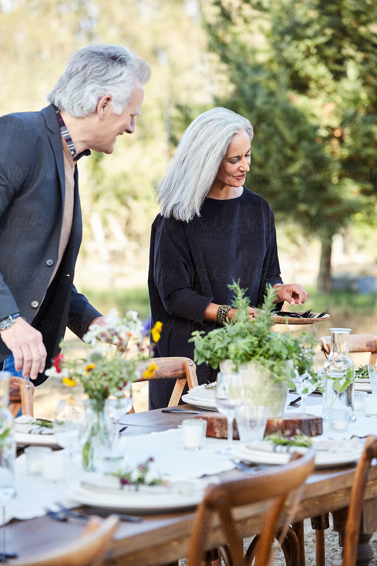 Senior couple setting the table for a Farm To Table dinner party at their home