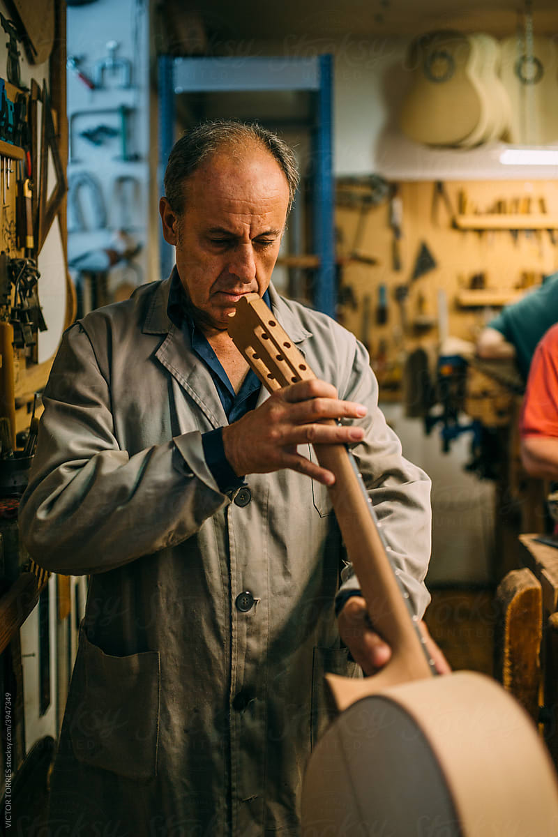 Senior luthier checking the finishing of a handcrafted spanish guitar