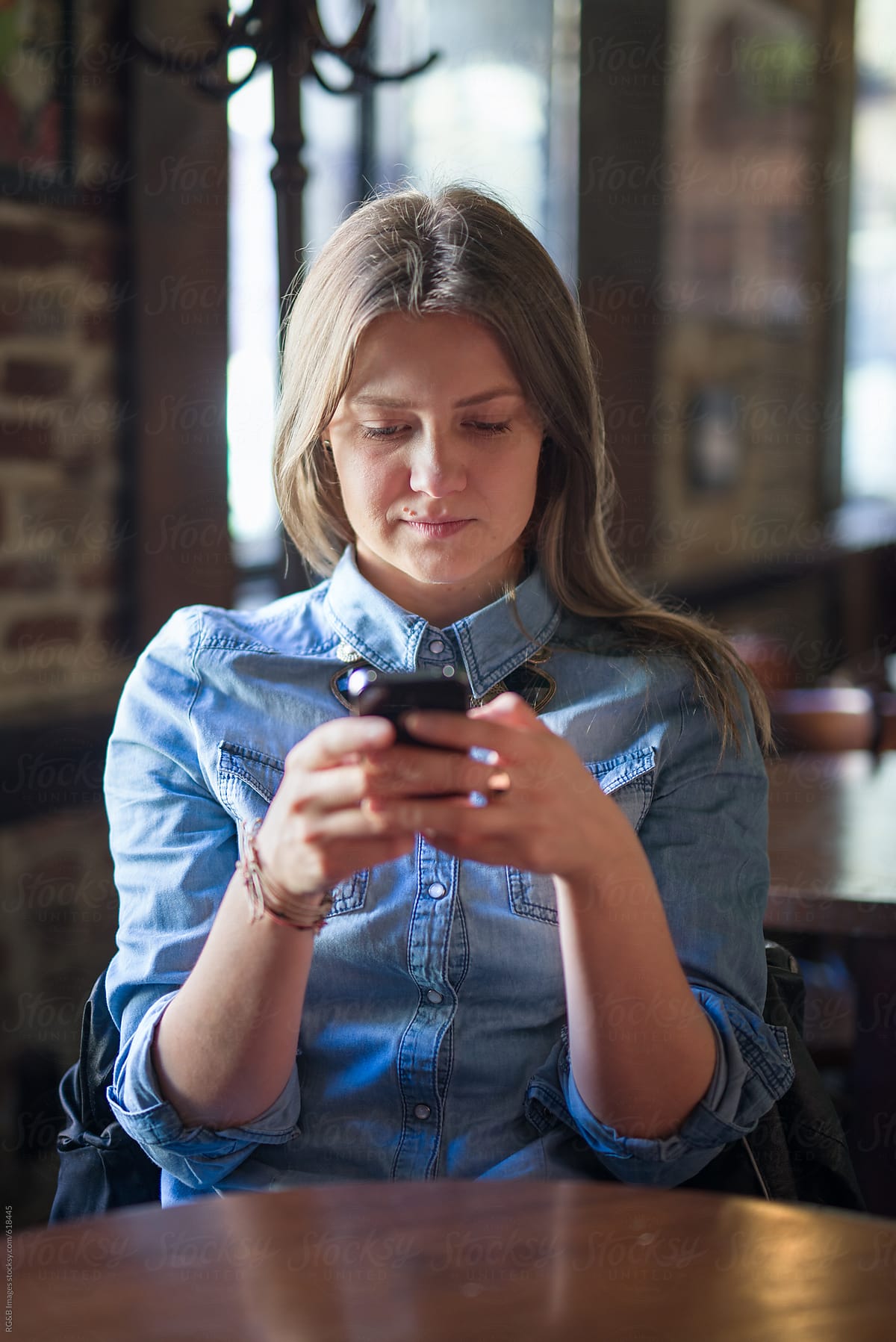 Young woman in a pub checking her mobile phone