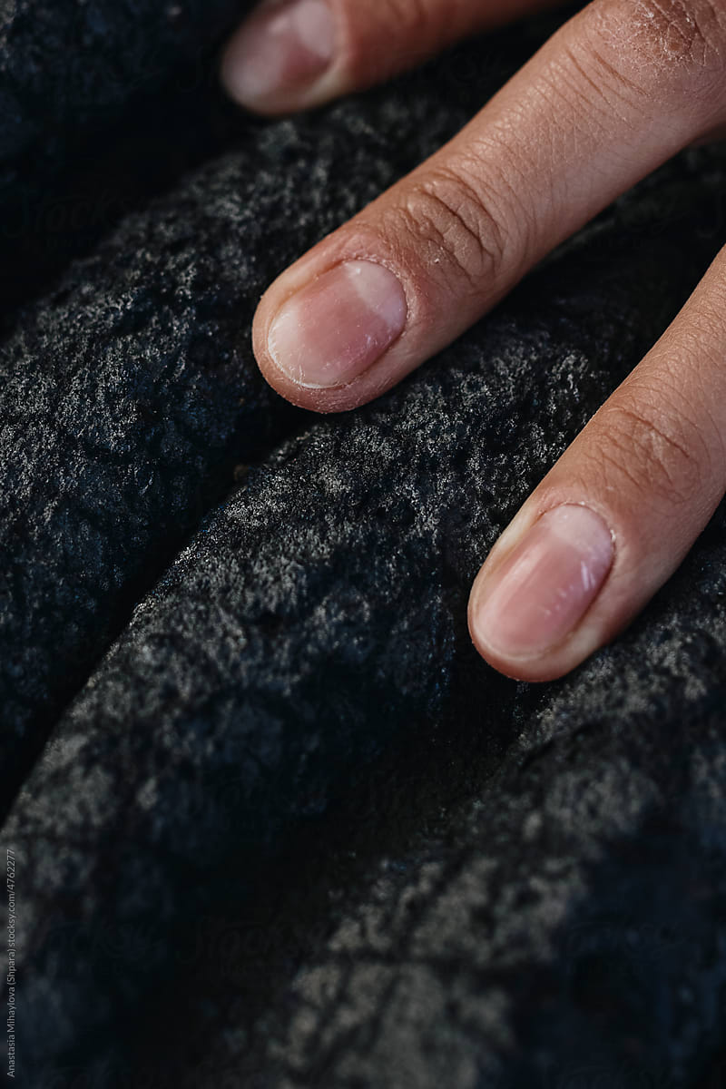 Close-up fingers of a young woman on black solid lava in Iceland