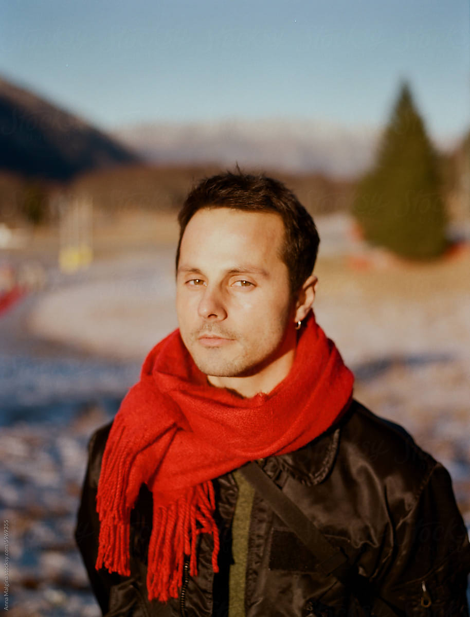 Man in Red Scarf Standing in Winter Landscape at Dusk
