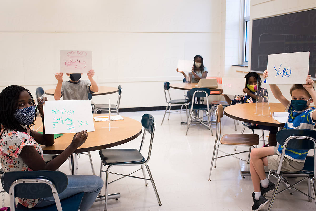Kids holding up answers on white boards