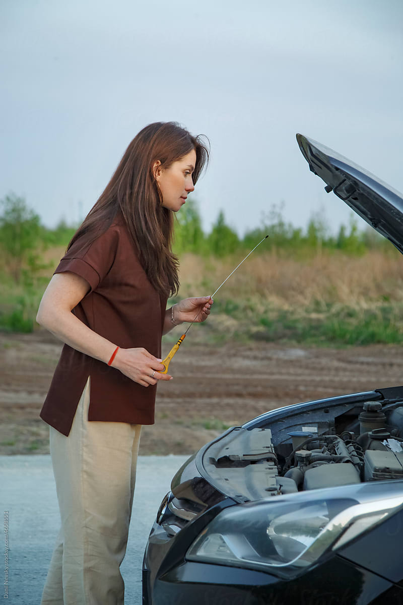 Female driver checking oil in car