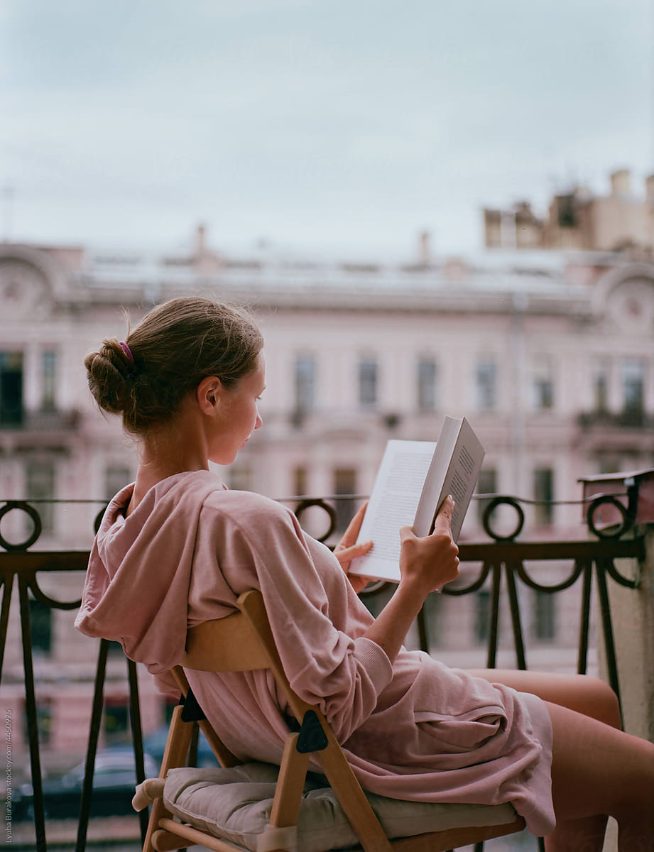 Woman reading a book on a balcony