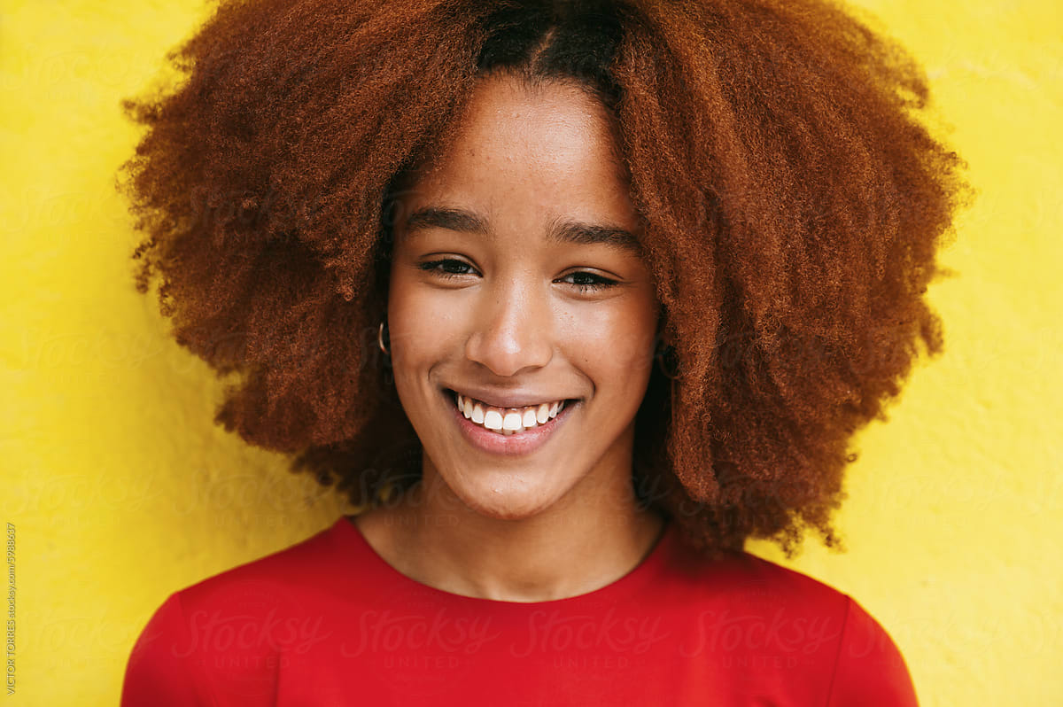 Joyful woman with curly hair against yellow backdrop
