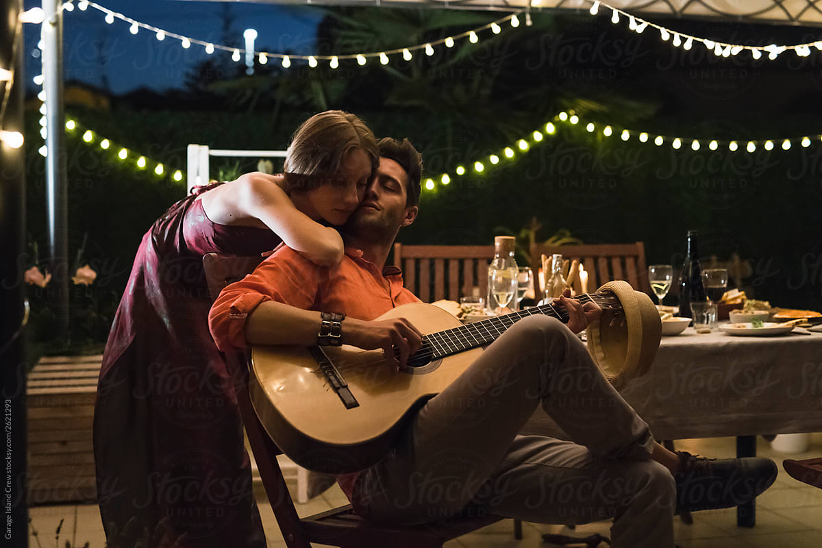 Romantic couple with guitar on the rooftop at night