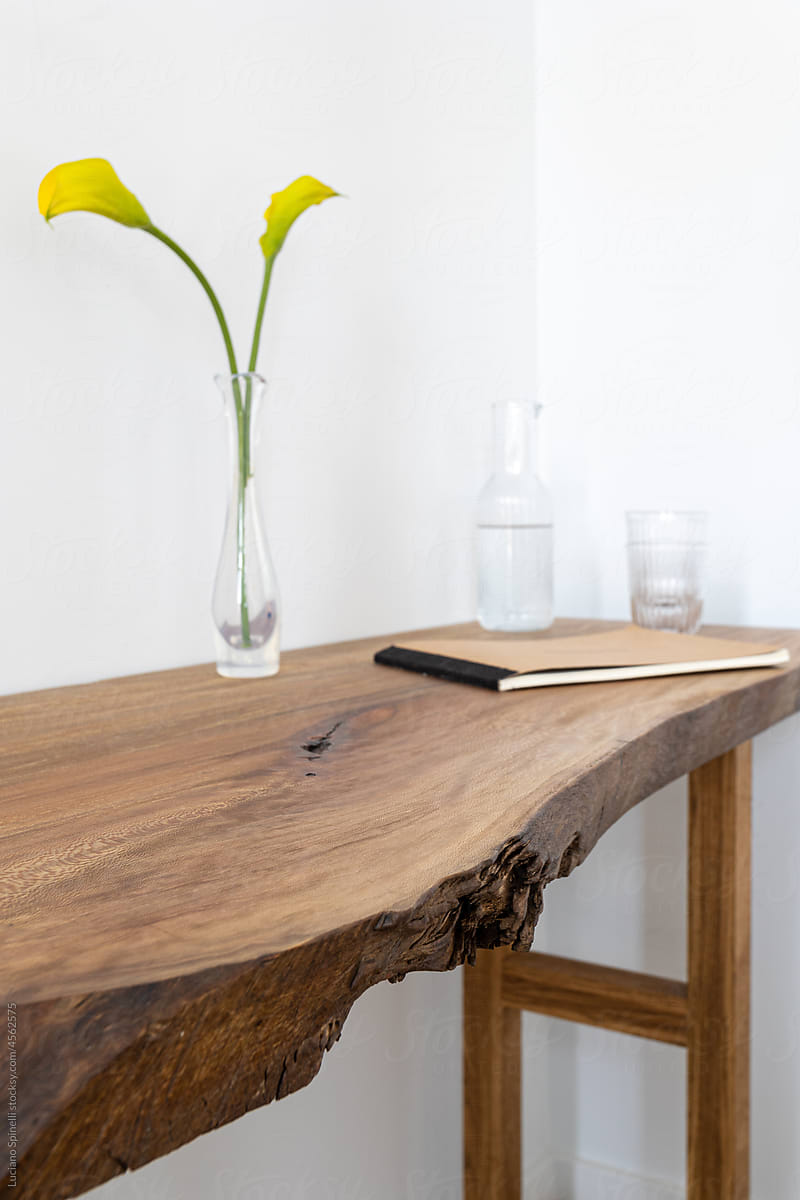 Cosy, minimalist workspace with wooden desk, water carafe and flowers