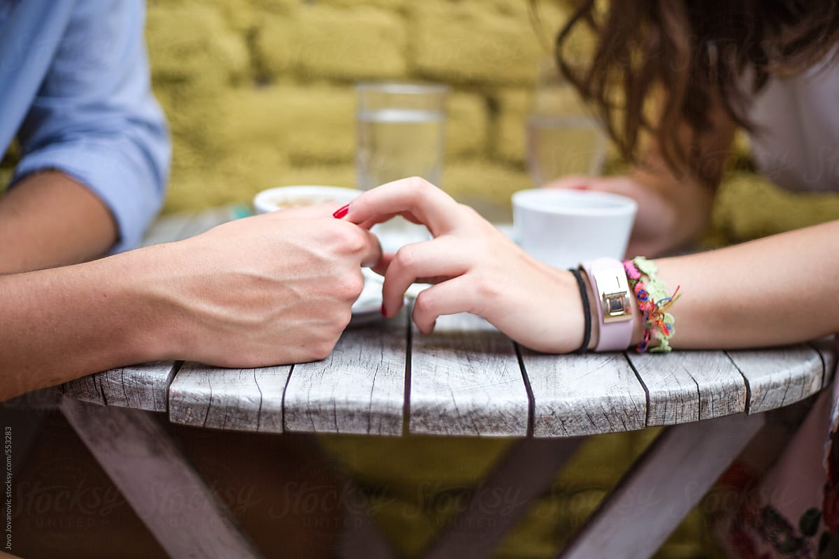 Closeup on couple\'s hands having coffee together