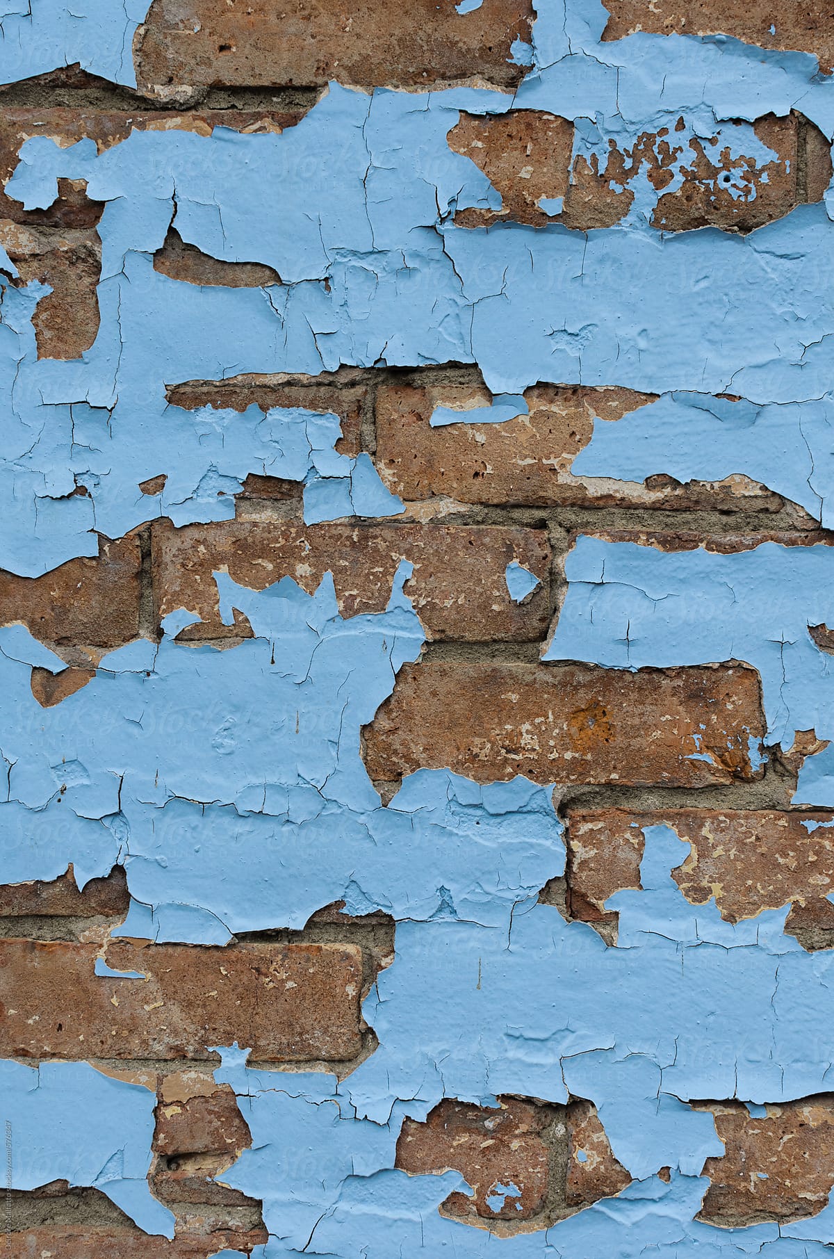 blue paint peeling off an old brick wall