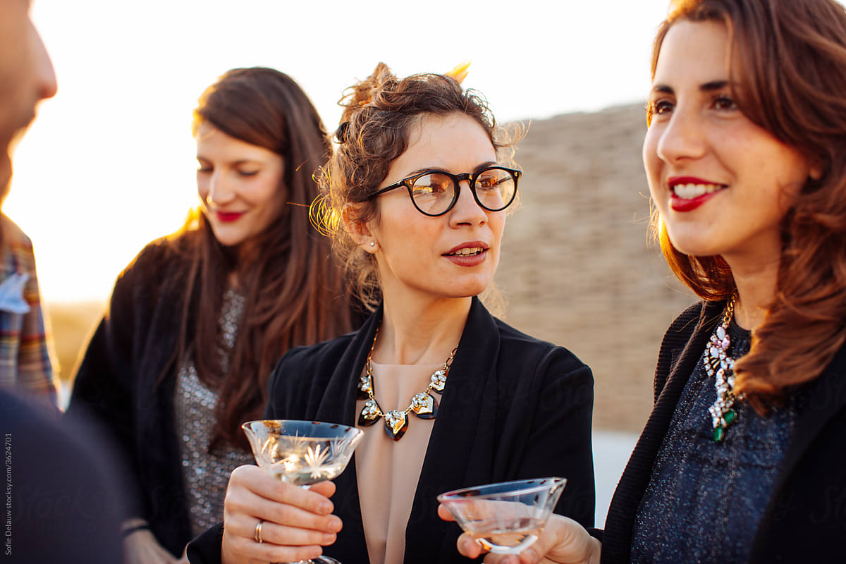 Crop content women talking to unrecognizable colleague during party outdoors