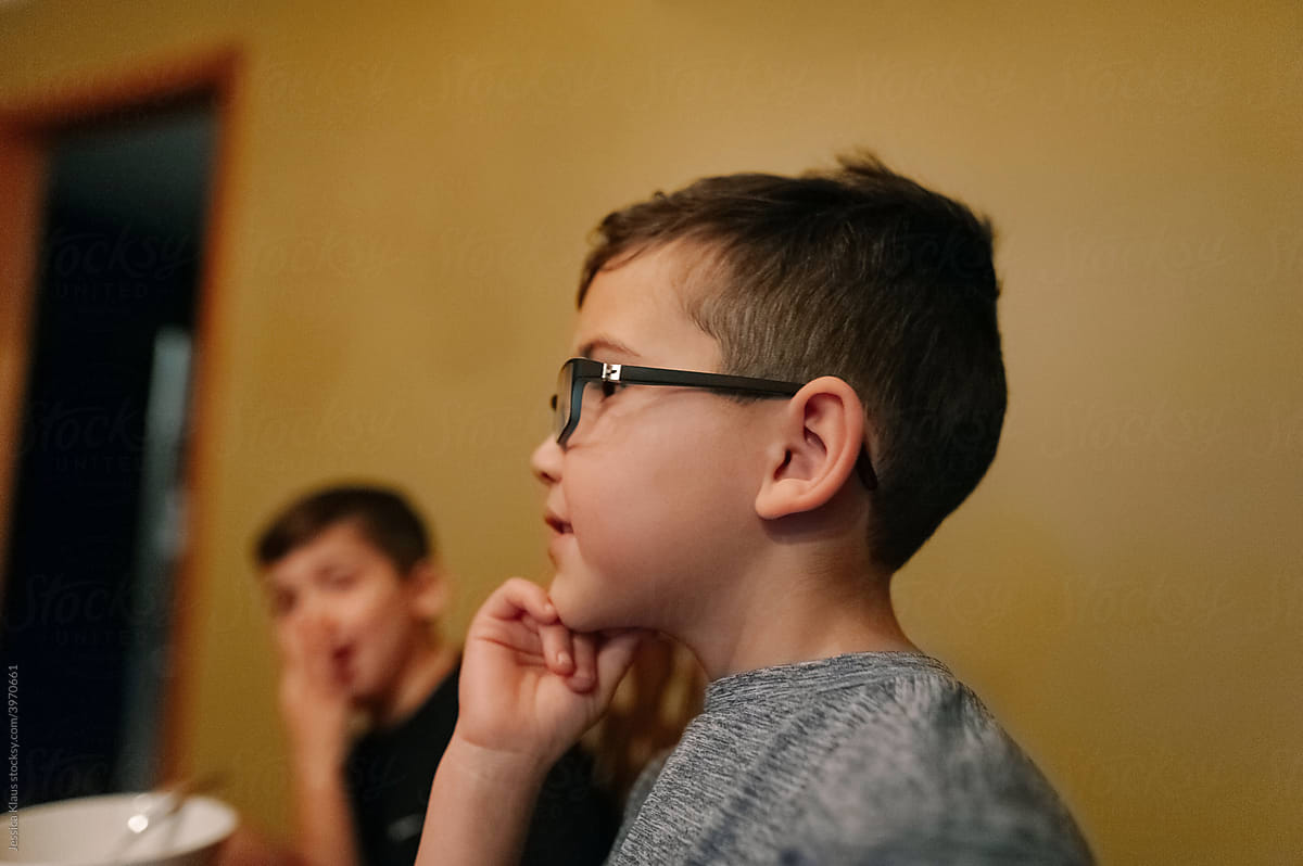 Side profile of a boy sitting in the dining room.