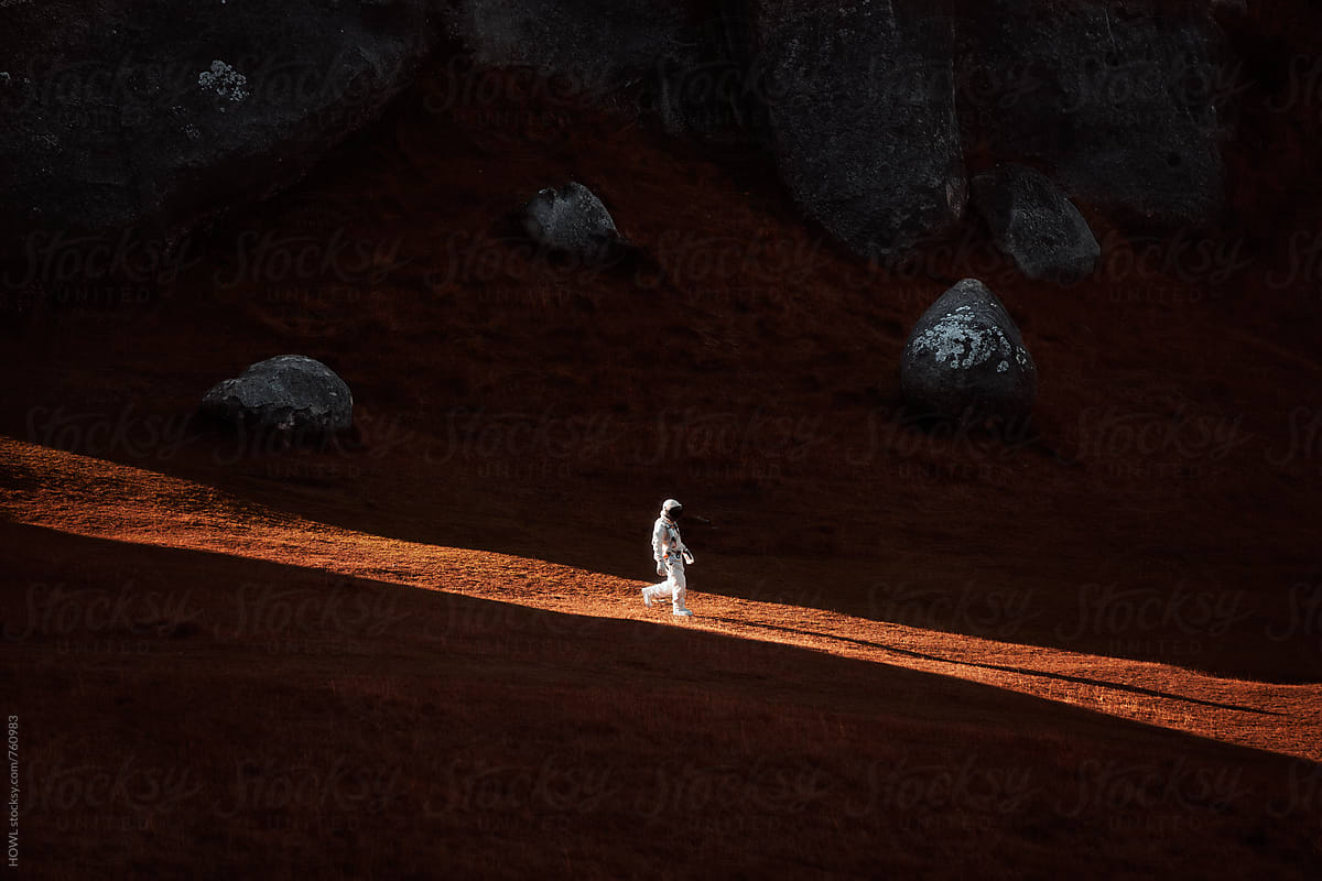 A lone astronaut descends the side of a mountain.