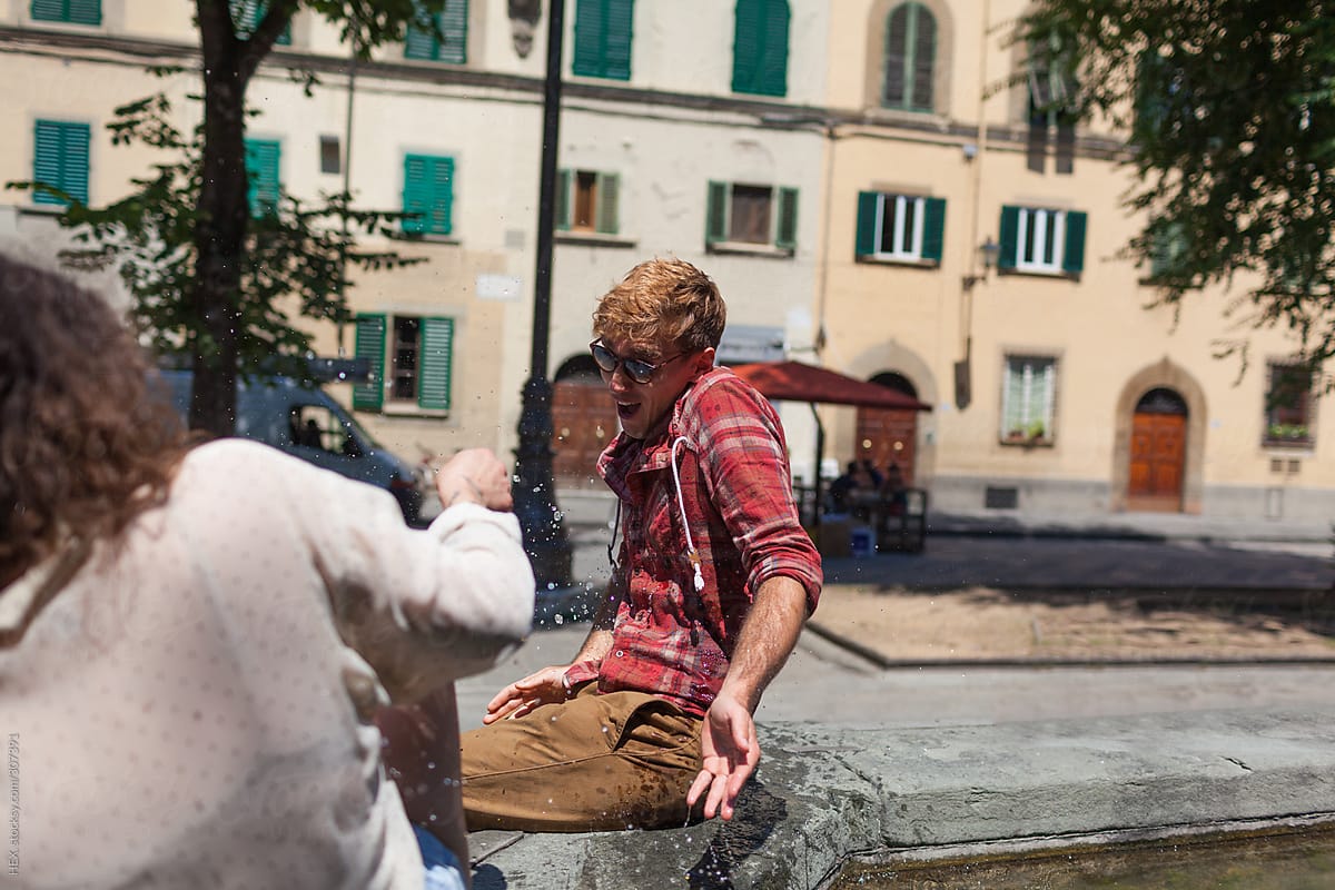 Young Couple Playing With Water Fountain In Piazza Santo Spirito Florence . Tuscany Italy