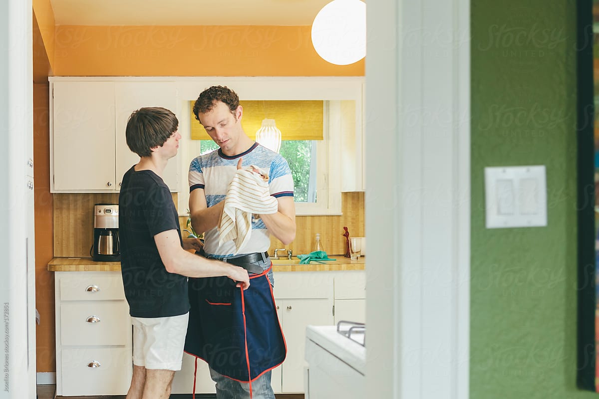 Gay Men Couple Talking After Doing Chore Of Washing Dishes In Kitchen