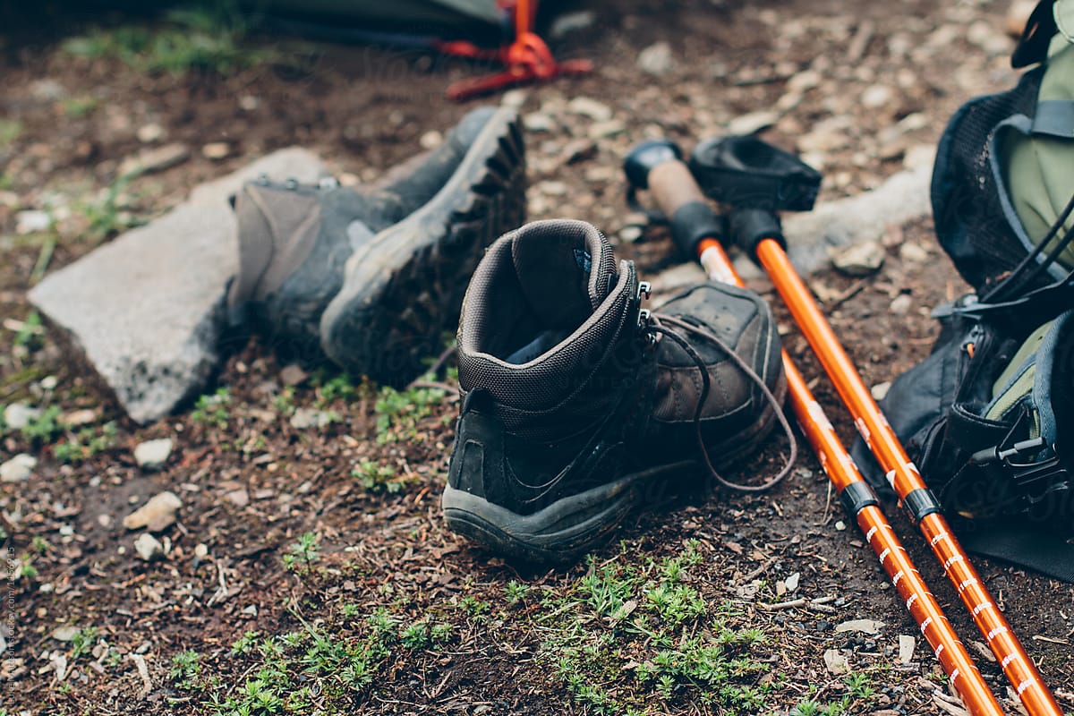 Hiking Boots And Trekking Poles Lying Next To Backpack