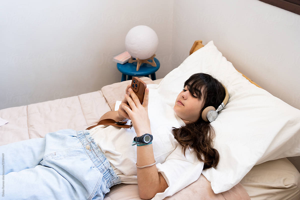 Teen girl with phone and headset in her bedroom
