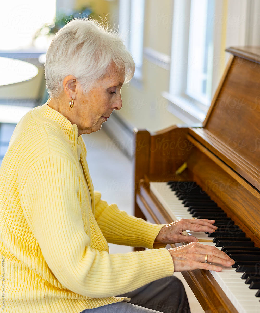 Retired  Senior Citizen woman at Home playing piano keyboard