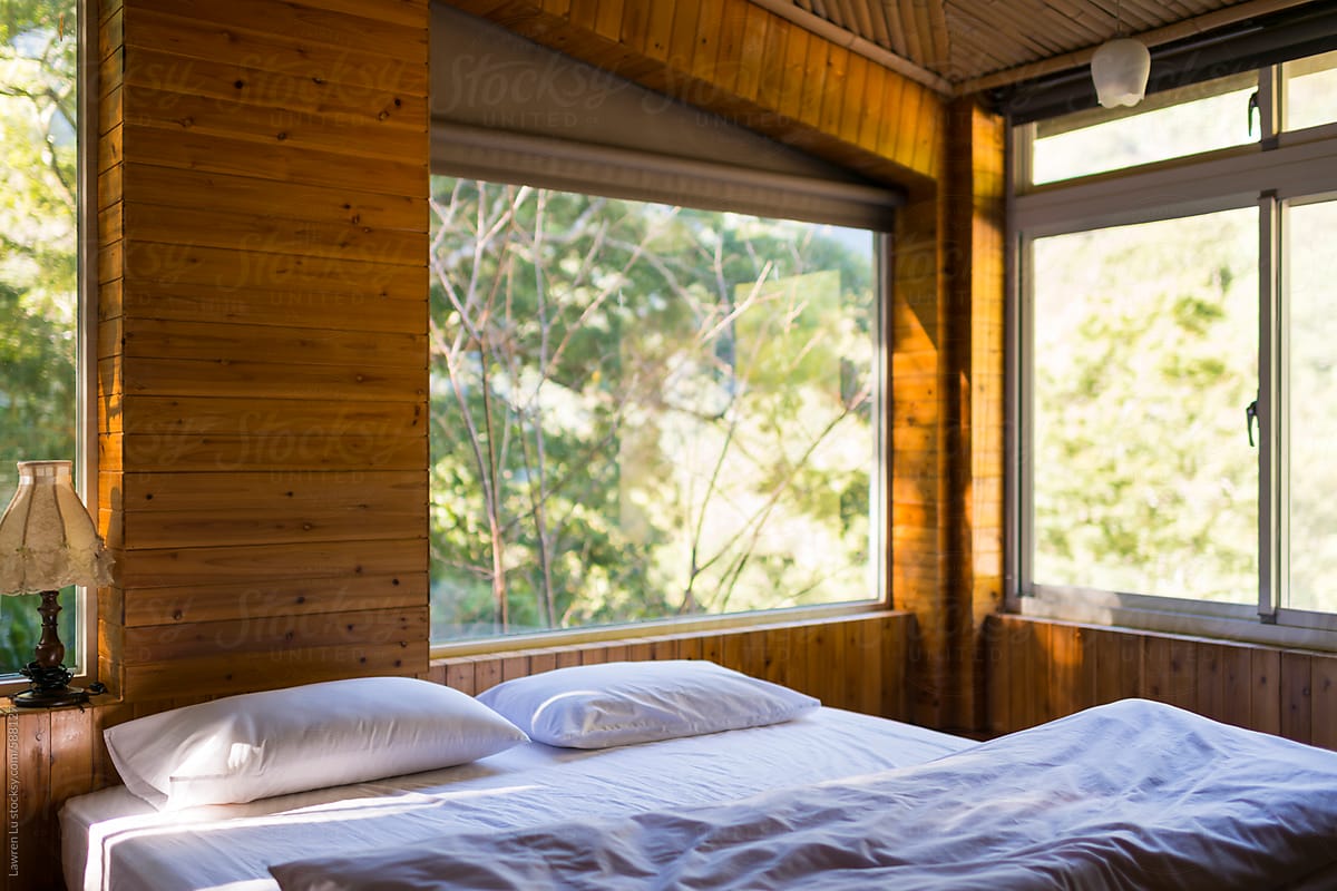 Bedroom with white bed and big window of view in forest