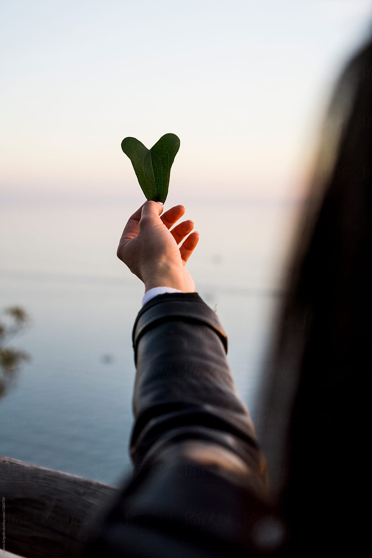 Woman holding a leaf. Heart shape.