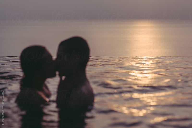 Anonymous Couple Kissing In The Pool At Sunset By Mosuno Summer Stocksy United