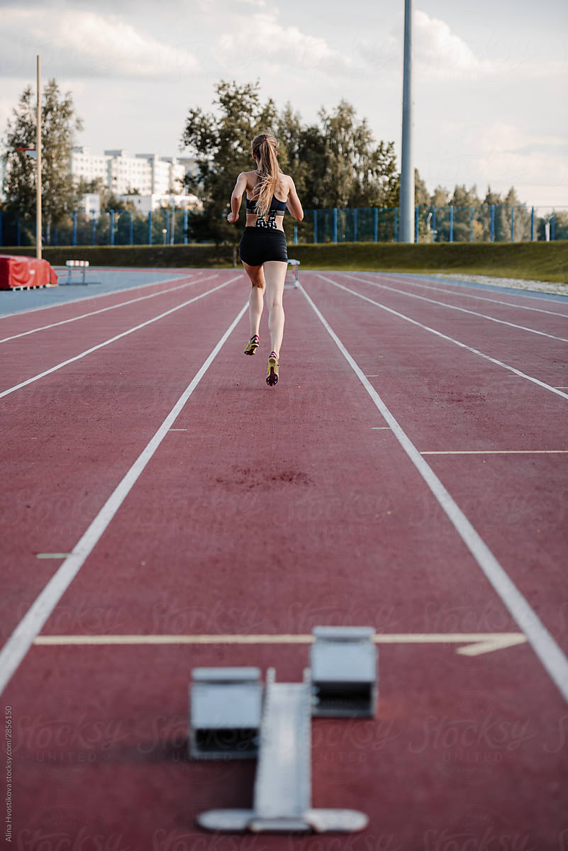 Female jogger starting run on stadium track