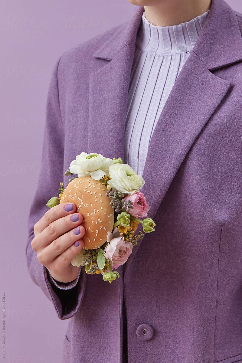 Woman in purple jacket holding burger with peonies
