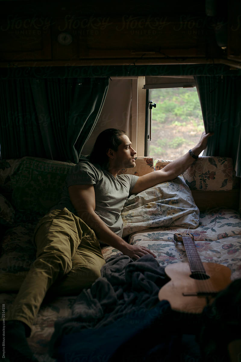 guy  lying on the bed with a guitar in a trailer