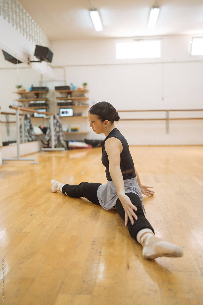 Slim woman practicing splits in ballet studio