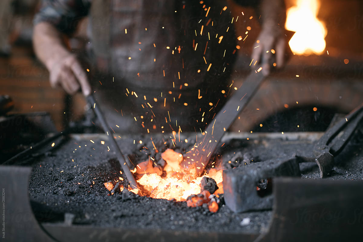 Crop blacksmith heating metal in coal