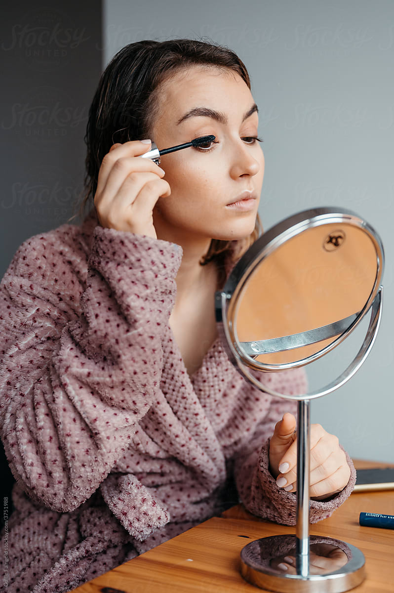 Woman painting eyelashes with mascara.